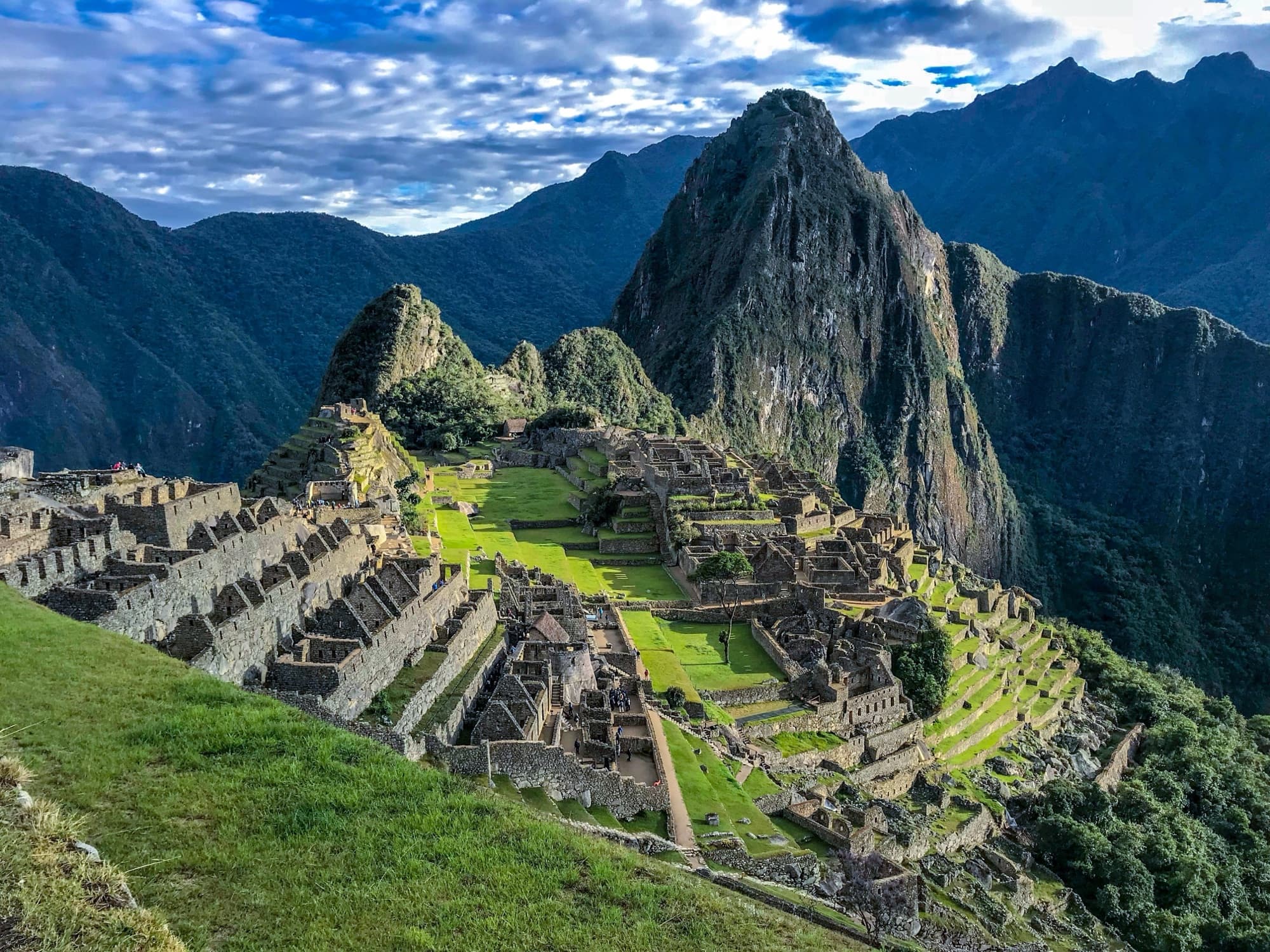 Machu Picchu at golden hour, the Inca citadel terraced into the green ridge above the Urubamba valley in Peru.