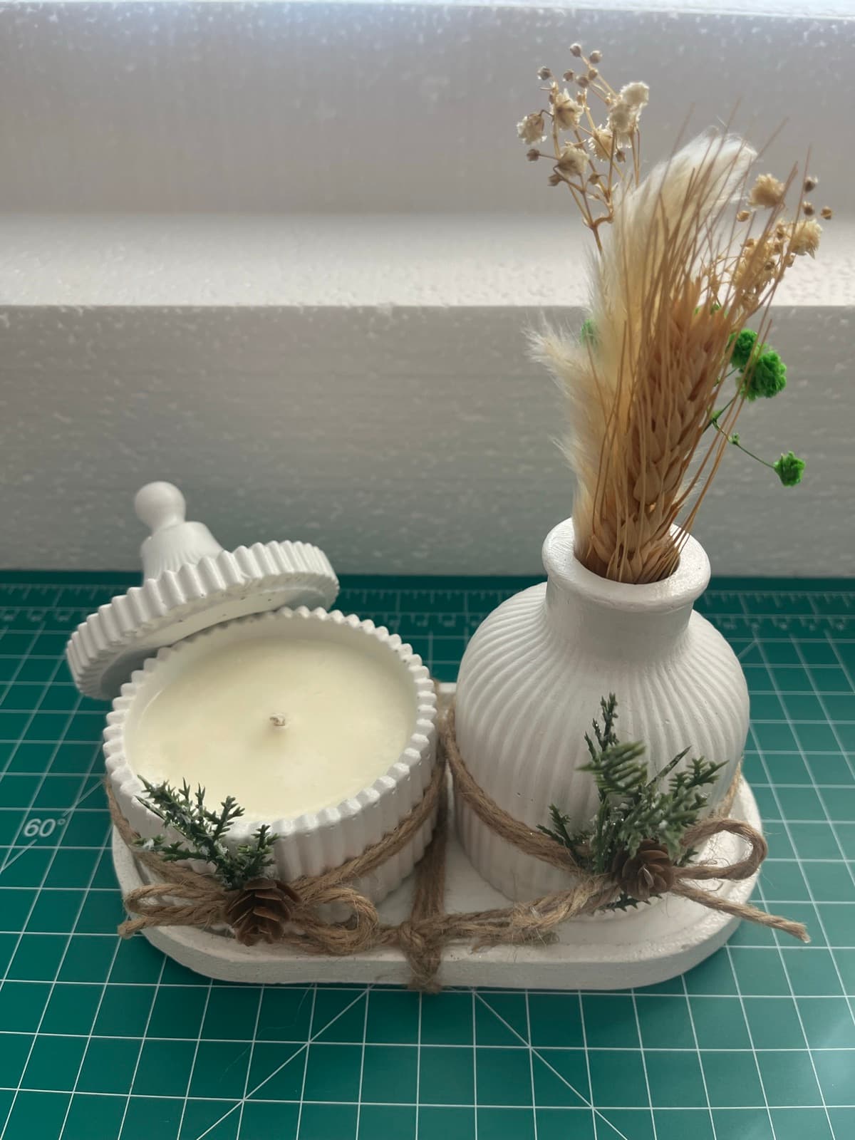 White cement set: a ribbed bud vase with dried wheat and a lidded candle on a matching tray, tied with jute